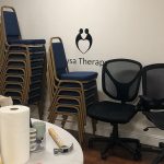 The Nysa Therapy logo is on the wall with chairs stacked in front of it.