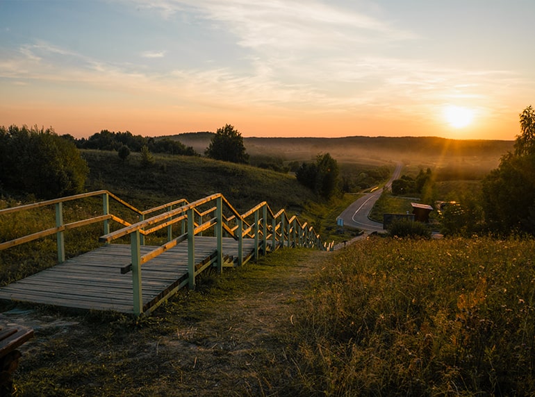 a wooden path leading you through the grass down to the beach